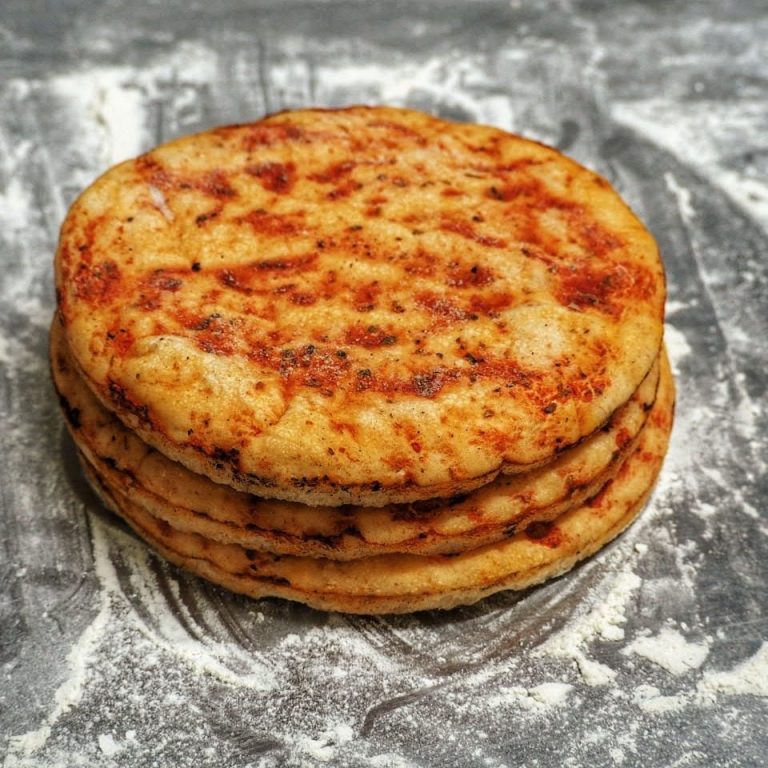 Pizza con una base dorada y un patrón espiral de salsa de tomate. Estirada a mano. Horneada sobre piedra.